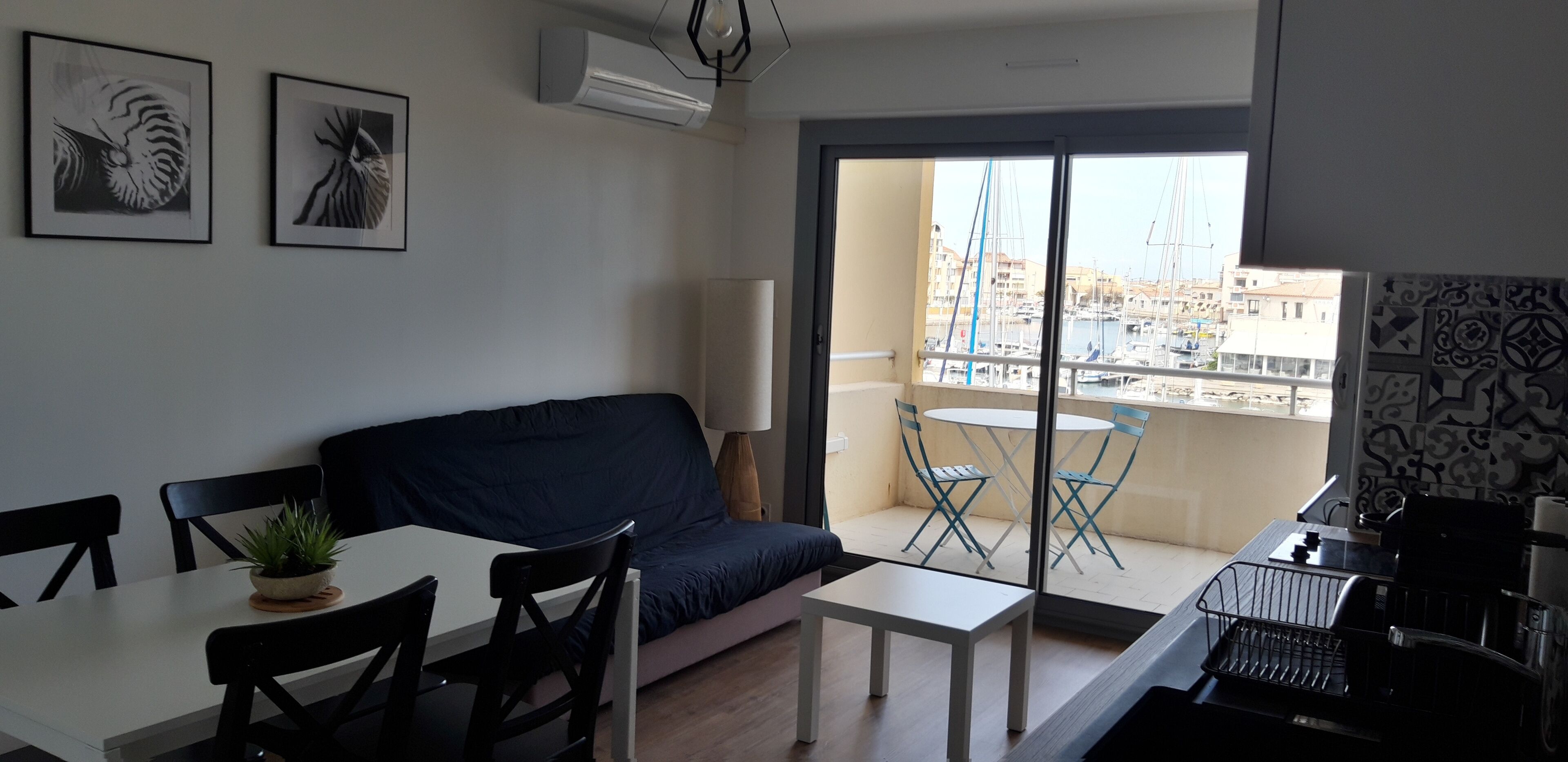 A compact living space with a balcony, a dining area, and a sofa.