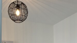 Een kamer met een grijze matras, een wandlamp en een lijst met een afbeelding van een plant.