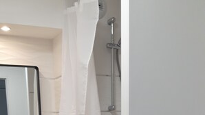 Een badkamer met douche, toilet en wastafel.