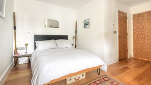 A bedroom with a bed, bedside table, lamp, and a wooden wardrobe. - Lyme Time (Lyme Regis)