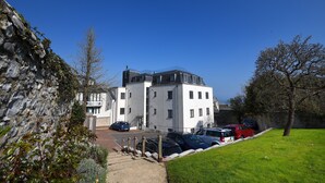 A modern building with a parking area and a stone wall. - Lyme Time (Lyme Regis)