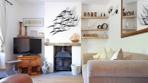 A cozy living room with a television, a fireplace, and a sofa. - Bethel Cottage (Lyme Regis)
