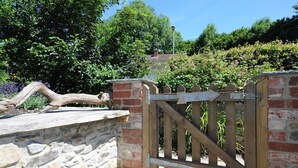 A rustic wooden gate with a brick wall and a stone ledge. - Bethel Cottage (Lyme Regis)