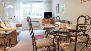 A dining area with a round table, chairs, and a television in the background. - 44 Fernhill Heights (Bridport)