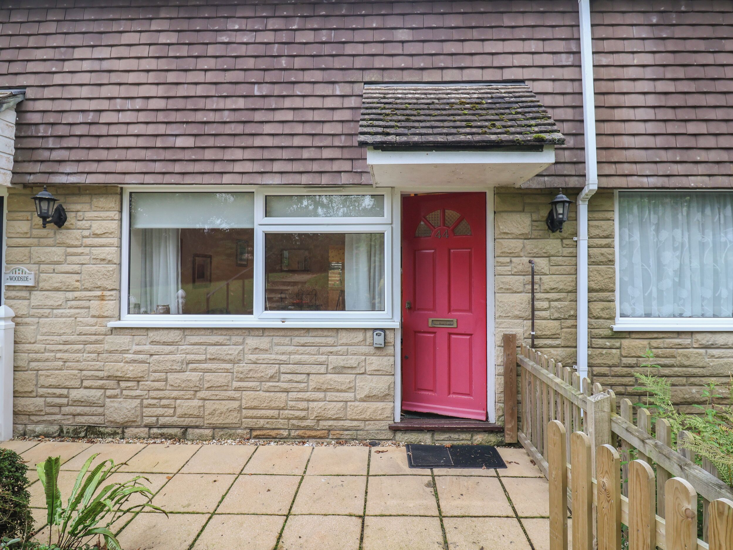 A house with a red door, a window with a white frame, and a stone wall.