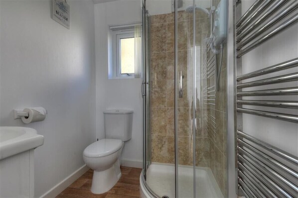 A bathroom with a toilet, a sink, a shower with glass doors, and a window.