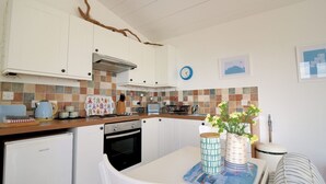 Een compacte keuken met witte kastjes, een betegelde achterwand en een eethoek met een tafel en stoelen.