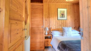 A wooden-paneled room with a bed, a nightstand, a lamp, and a framed picture on the wall. - 4 Pinewood Retreat (Axminster)