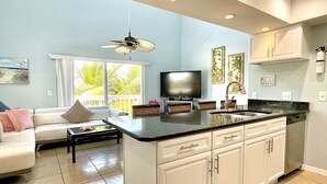 A modern kitchen with white cabinets, a black countertop, and a built-in dishwasher.