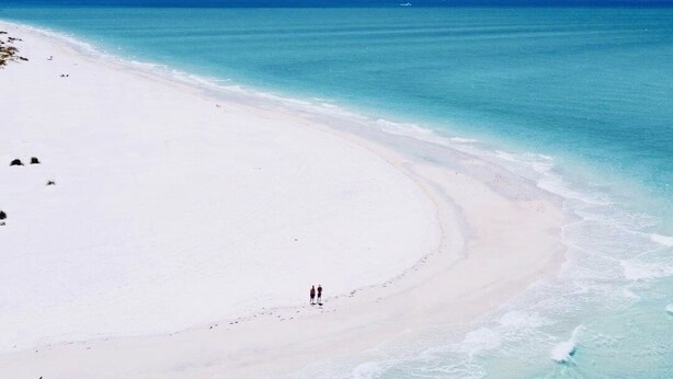 A beach with a clear turquoise sea and a white sandy shore.