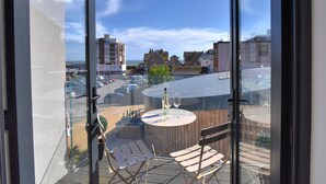A balcony with a table and chairs, overlooking a parking lot and buildings. - 3 Grove Mews (Seaton)