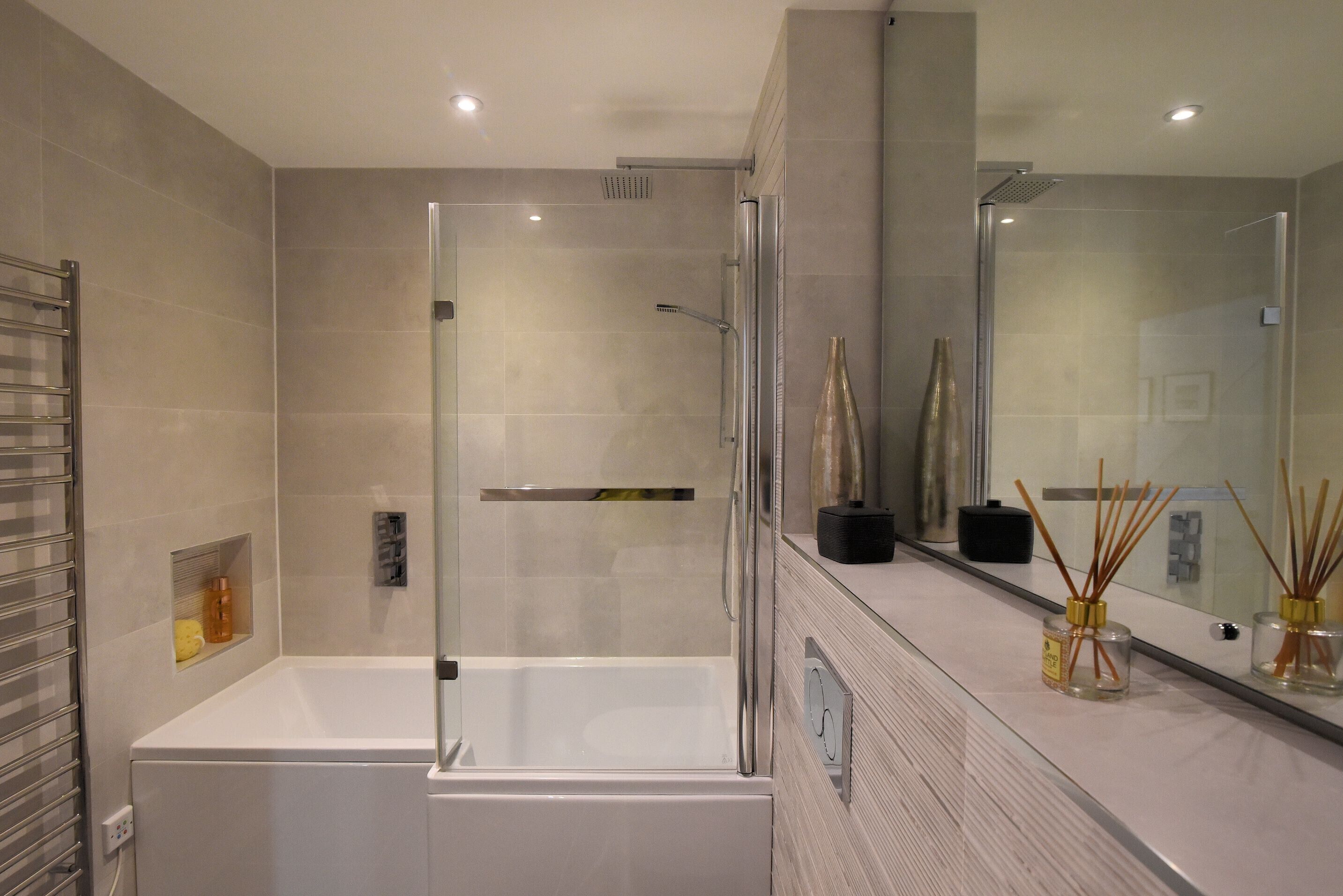 A modern bathroom with a glass-enclosed shower, a white bathtub, and a large mirror.