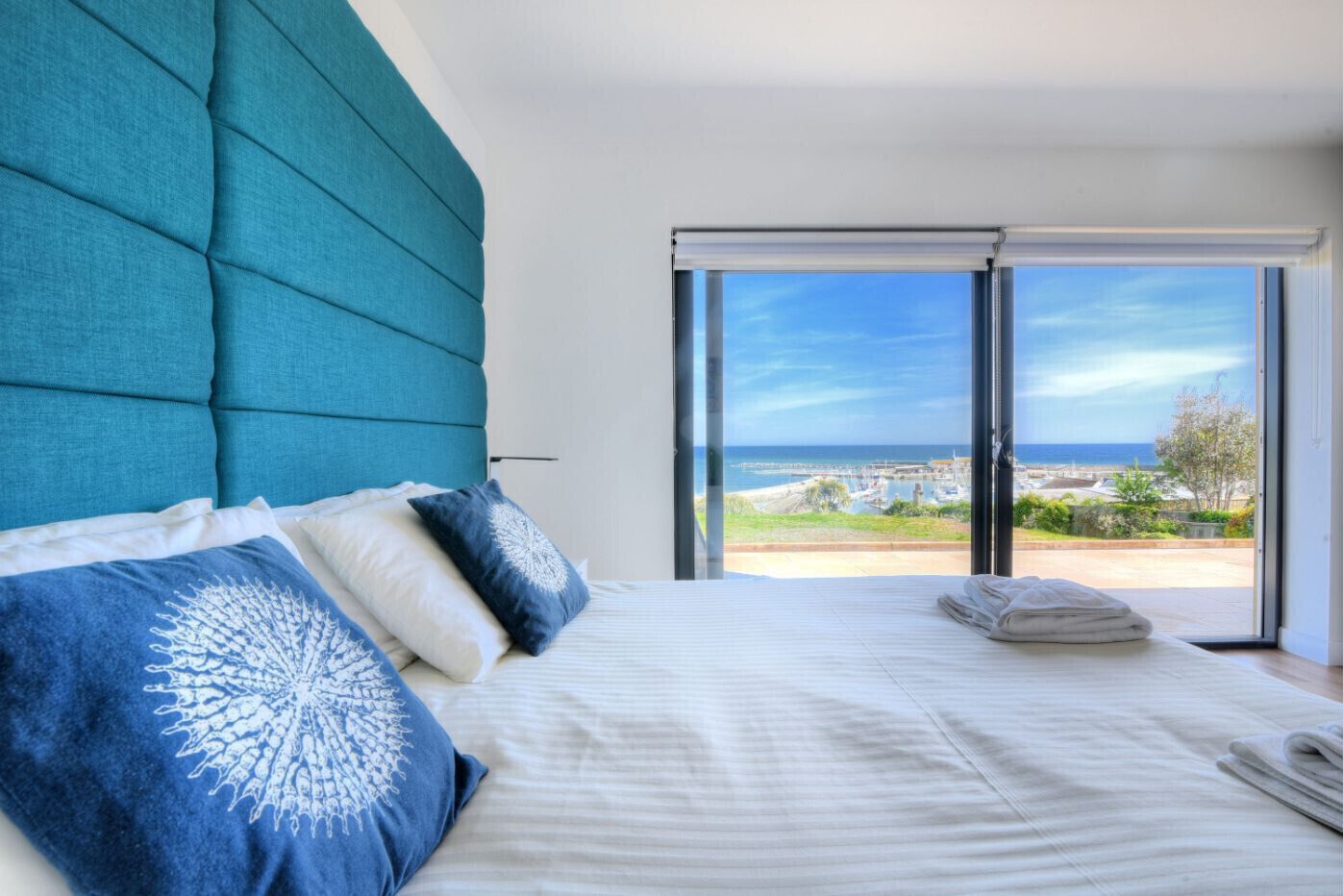 Un dormitorio con una cama grande, vista al mar y una puerta corrediza de vidrio.