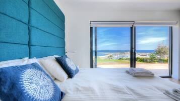 Un dormitorio con una cama grande, vista al mar y una puerta corrediza de vidrio.