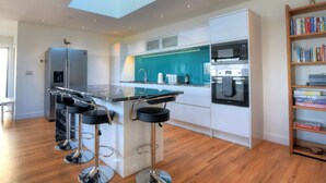 A modern kitchen with a skylight, stainless steel appliances, and a bar area with stools. - Harbour Heights Cottage (Lyme Regis)