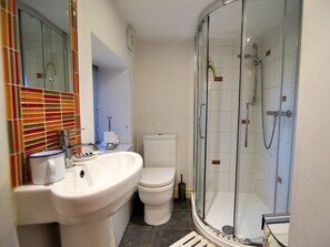 A bathroom with a white sink, a toilet, and a glass-enclosed shower. - Little Bay View (Lyme Regis)