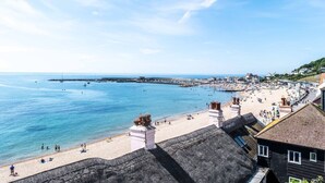 A coastal town with a beach, a pier, and buildings along the shore. - 3 Beach Way House (Lyme Regis)