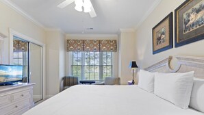 A hotel room with a large bed, a television on a dresser, a desk with a chair, and two framed pictures on the wall. - Stunning 3BR Condo Magnolia Point (Myrtle Beach)