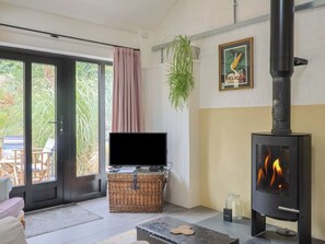 A living room with a television, a fireplace, a wicker basket, and a sliding glass door leading to an outdoor area.