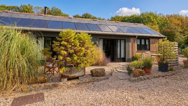 A house with a sloped roof, solar panels, and a gravel driveway.