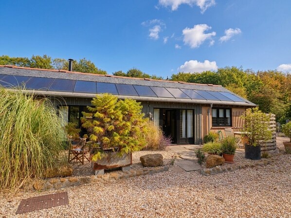 Une maison avec un toit en pente, des panneaux solaires et une allée gravillonnée.