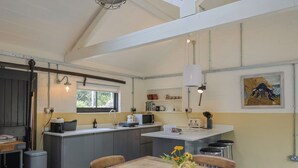 A compact kitchen with a central island, a dining table with a vase of flowers, and a painting on the wall.