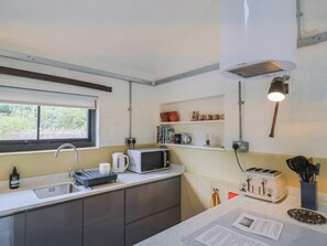 A compact kitchen with a sink, a microwave, a toaster, and a kettle.