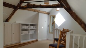 A bedroom with a loft bed, a wooden chair, a white wardrobe, and a mirror. - Tudor Cottage (Lyme Regis)