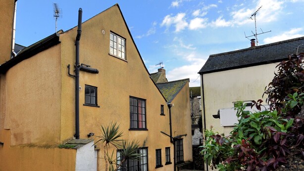 A traditional building with a gabled roof, multiple windows, and a chimney. - Tudor Cottage (Lyme Regis)