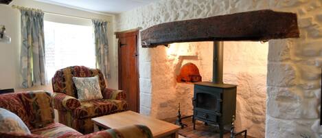 A cozy living room with a stone fireplace, patterned armchairs, and a wooden coffee table.