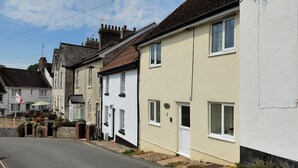 A row of traditional buildings with a narrow street. - Smugglers Cottage (Seaton)