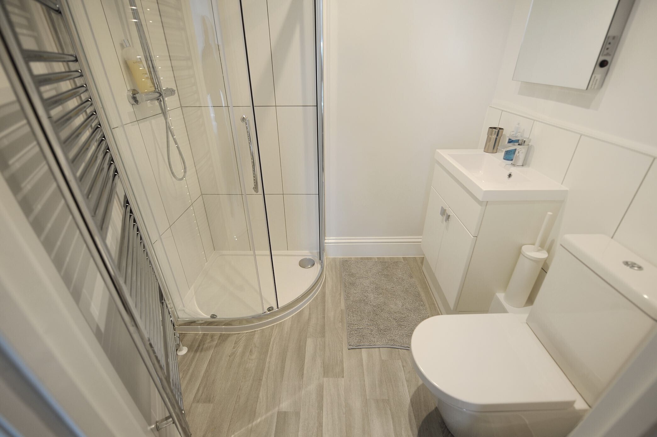 Une salle de bain avec une douche à parois de verre, des toilettes et un lavabo équipé de produits de toilette.