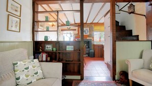 A cozy living room with a wooden bookshelf, a sofa, and a patterned throw pillow. - Lavender Cottage (Lyme Regis)