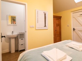 Un dormitorio con cama, mesita de noche, lavamanos y puerta.