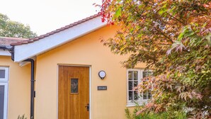 Un bâtiment jaune avec une porte en bois, une fenêtre et une enseigne sur laquelle on peut lire « ÉCURIES ».