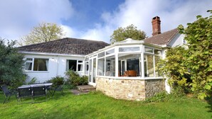 Uma casa com solário, jardim e um pátio com mobiliário de exterior.