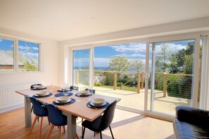 A dining area with a table set for six, large windows, and a view of the outdoors. - Lottys Lookout (Lyme Regis)