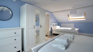 A bedroom with a large wardrobe, two beds, a mirror, and a skylight. - 7 Seafield Road (Seaton)
