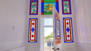 A hallway with a white door leading to a room. There are colorful stained glass windows above the door. - 7 Seafield Road (Seaton)