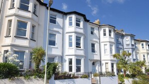 A row of white terraced houses with bay windows, a street lamp, and a white wall with plants. - 7 Seafield Road (Seaton)