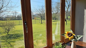 A room with large windows offering a view of a grassy field and trees. - The Cider House (Axminster)