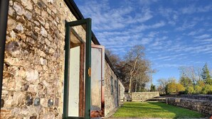 A stone building with a wooden door and a grassy courtyard. - 2 Home Farm South (Lyme Regis)