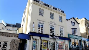 A building with WHSmith and QUBA & CO. stores on the ground floor. - No. 2, 26 Broad Street (Lyme Regis)