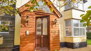 A wooden front door with a glass panel, a small porch with steps, and a potted plant. - Hove To (Lyme Regis)