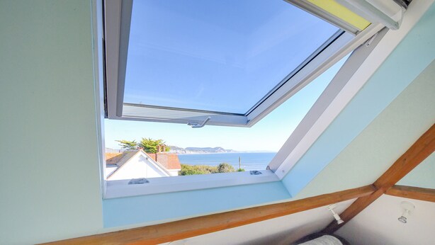 A room with a skylight overlooking a coastal view. - Hove To (Lyme Regis)