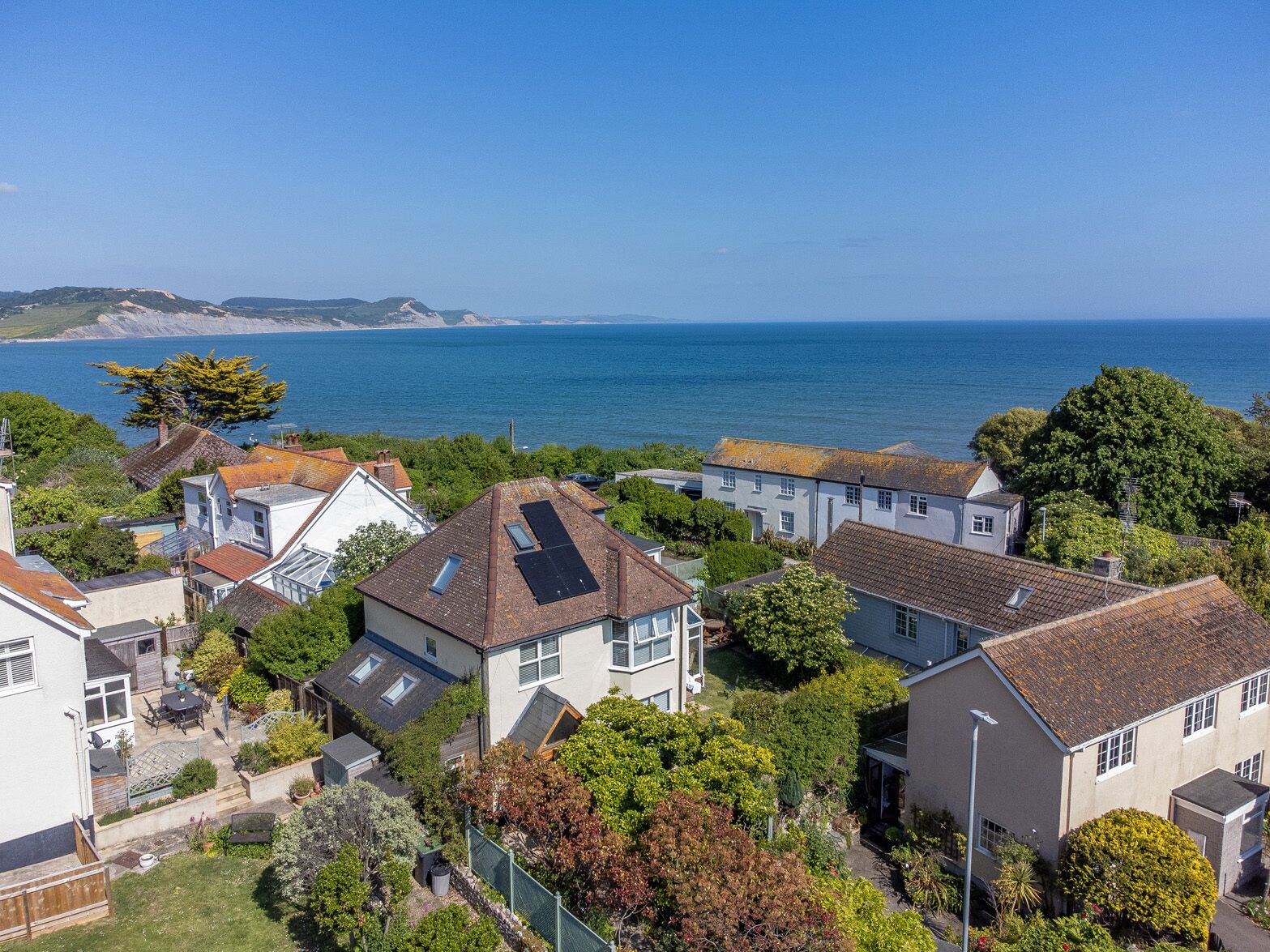A residential area with houses, a garden, and a view of the sea.