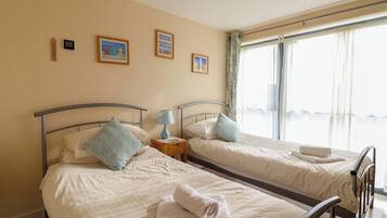 Habitació d'hotel amb dos llits, una finestra amb cortines i una obra d'art a la paret.