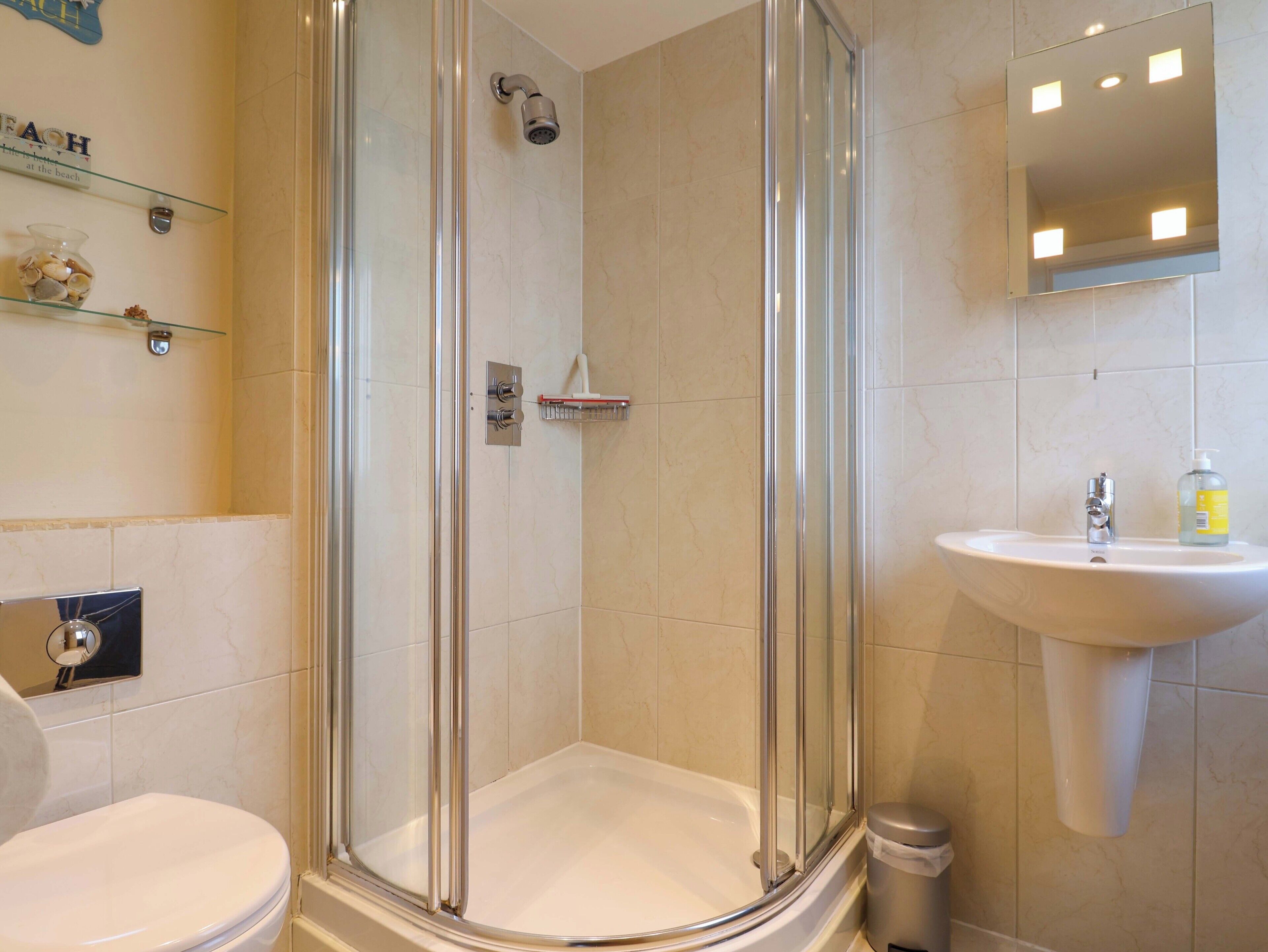 A bathroom with a glass-enclosed shower, a sink, and a toilet.