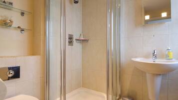 Une salle de bain avec une douche à parois de verre, un lavabo et des toilettes.