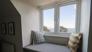 Asiento junto a la ventana con un banco acolchado, un cojín estampado y un cojín a rayas.